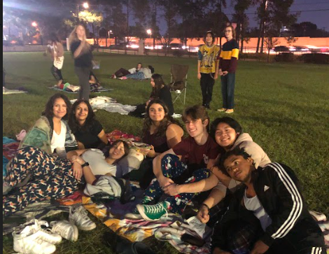 Students in pajamas lying on a blanket on the lawn just before the movie starts